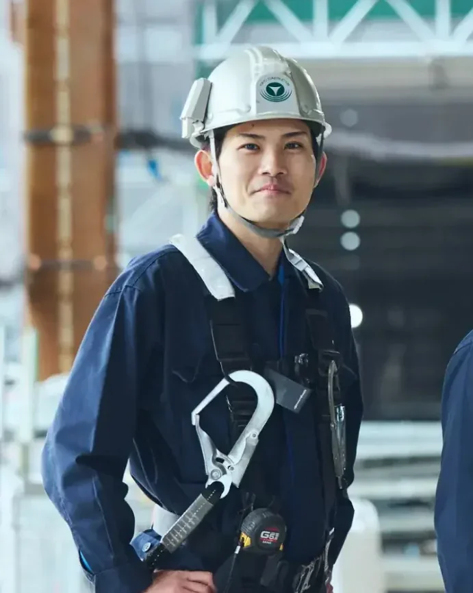 ヘルメットと安全帯を着用して笑顔の作業員