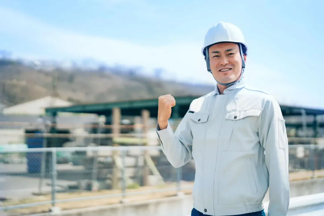 ヘルメットを着用して笑顔で前を向くスタッフ