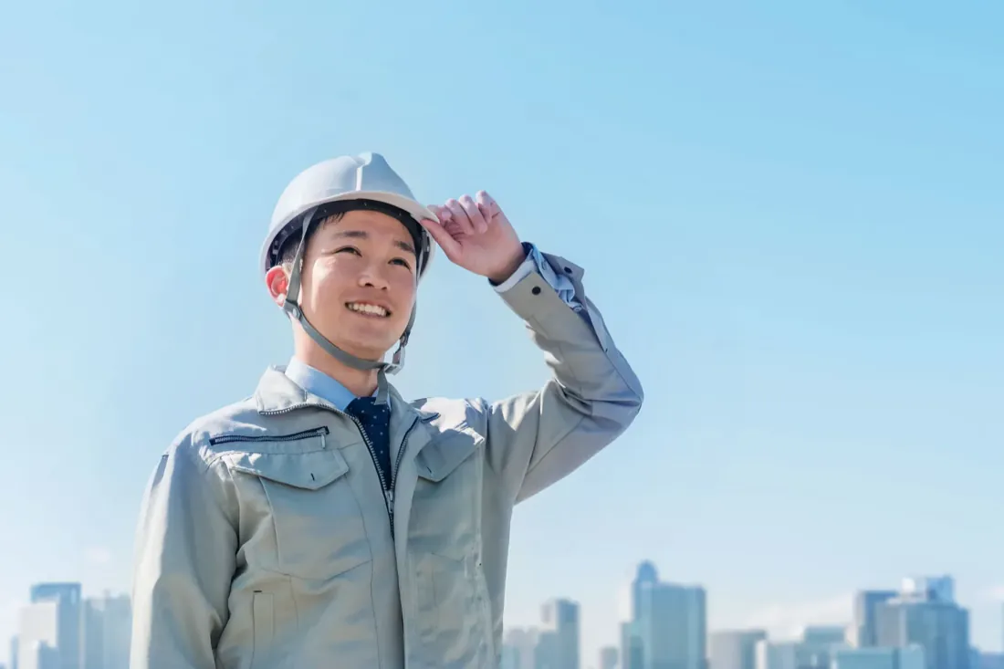 ヘルメットを着用して笑顔で前を向くスタッフ